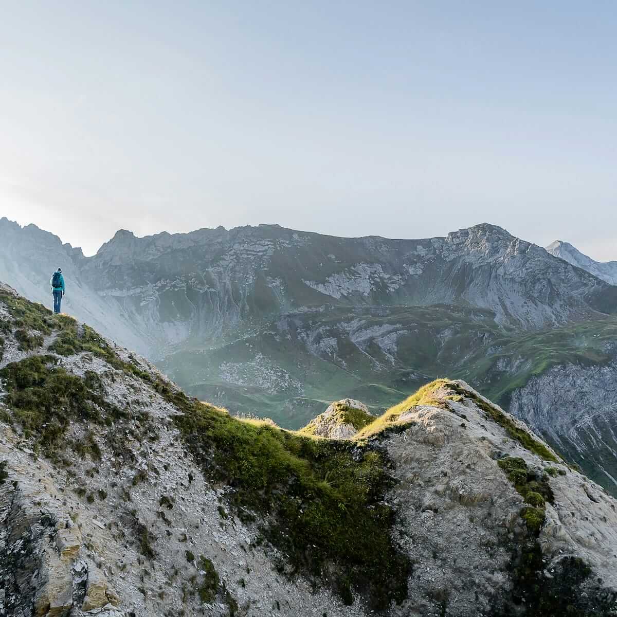 Wanderer auf Bergkamm mit Blick auf grüne Täler