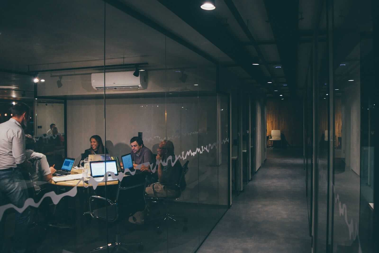 Teamarbeit im Büro bei Nacht mit Laptops.
